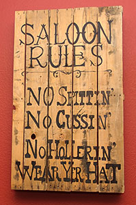 Rustic Saloon Rules Sign Wooden sign with 'Saloon Rules' written in rustic lettering: No Spittin’, No Cussin’, No Hollerin’, Wear Yer Hat.